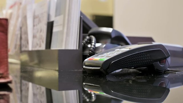 Close-up terminal card reader for credit card payment. A woman's hand is paying by applying a card to a paypass payment terminal in a store. Banking services of electronic money. Use Debit Card