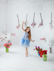 Portrait of a beautiful blue-eyed girl, a little girl among spring flowers in a bright room.