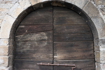 Fototapeta na wymiar Italy, Varenna, Lake Como, a wooden door with a latch under an arch