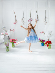 Portrait of a beautiful blue-eyed girl, a little girl among spring flowers in a bright room.