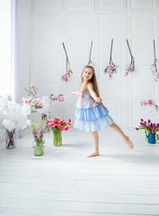 Portrait of a beautiful blue-eyed girl, a little girl among spring flowers in a bright room.