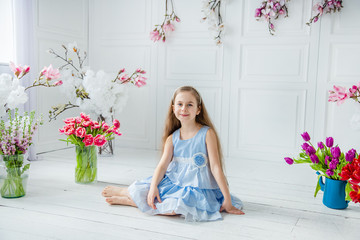 Portrait of a beautiful blue-eyed girl, a little girl among spring flowers in a bright room.