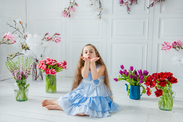 Portrait of a beautiful blue-eyed girl, a little girl among spring flowers in a bright room.