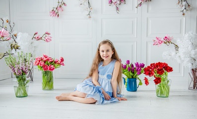 Portrait of a beautiful blue-eyed girl, a little girl among spring flowers in a bright room.
