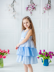 Portrait of a beautiful blue-eyed girl, a little girl among spring flowers in a bright room.