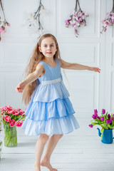 Portrait of a beautiful blue-eyed girl, a little girl among spring flowers in a bright room.