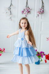 Portrait of a beautiful blue-eyed girl, a little girl among spring flowers in a bright room.