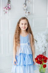 Portrait of a beautiful blue-eyed girl, a little girl among spring flowers in a bright room.