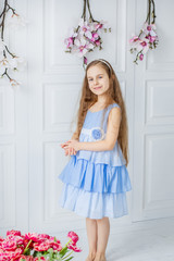 Portrait of a beautiful blue-eyed girl, a little girl among spring flowers in a bright room.