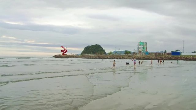 kids running in water near a small green island on the beach  