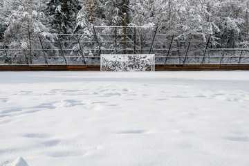 Snow covered soccer field and goal net, with forest background © knelson20