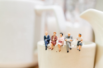 Miniature people : businessman and woman sitting on a cup of tea