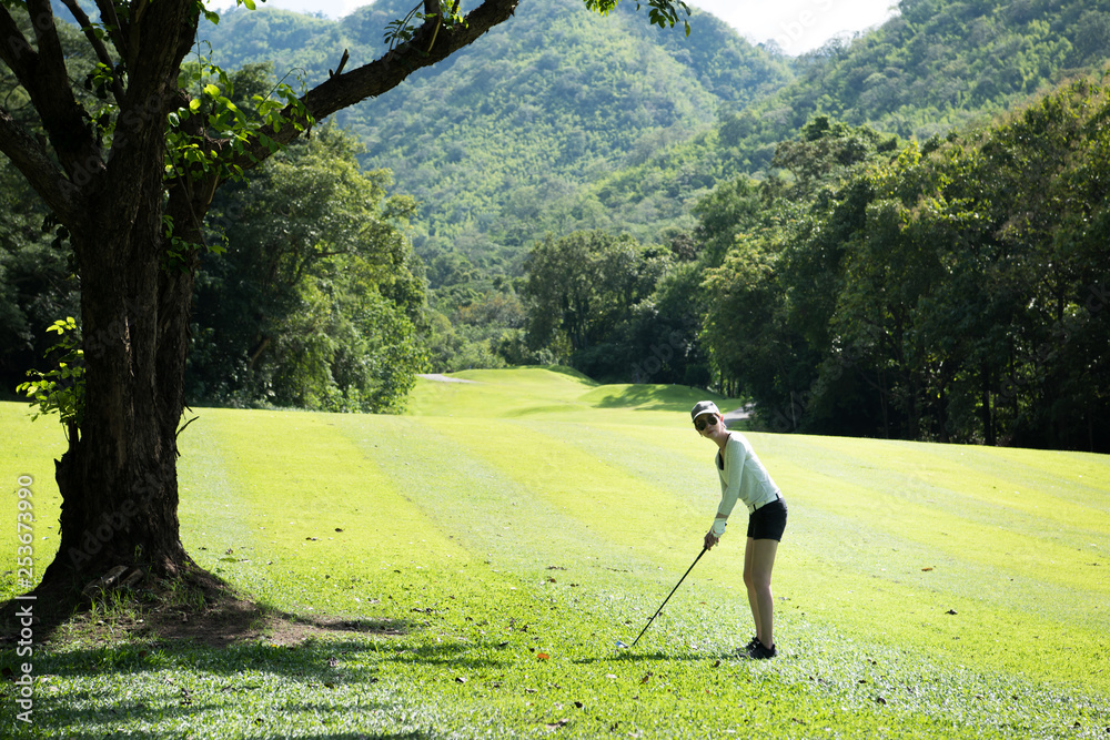 Wall mural Asian woman playing golf on a beautiful natural golf course