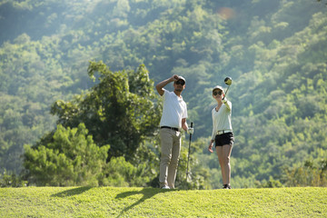 Man and woman playing golf on a beautiful natural golf course