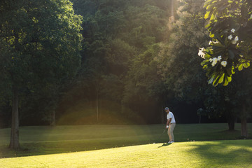 Young Asian man playing golf on a beautiful natural golf course