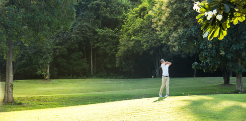 Young Asian man playing golf on a beautiful natural golf course