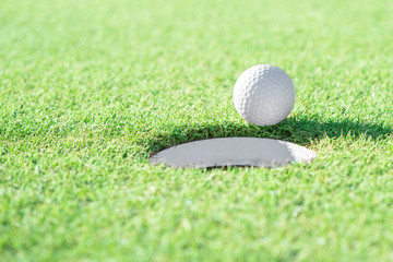 Golf ball and golf hole on green grass with copy space