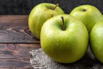 Green apples on dark wooden background.