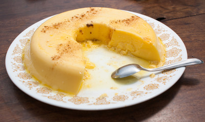 eating home made vanilla and cinnamon flan over a wooden table