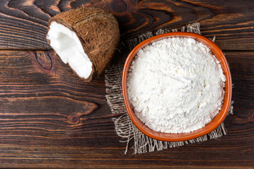Coconut flour on dark wooden background.