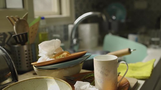 Slow pan over a sink full of dirty dishes in the kitchen