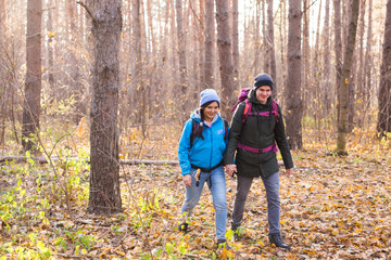 Fototapeta premium adventure, travel, tourism, hike and people concept - smiling couple walking with backpacks over natural background