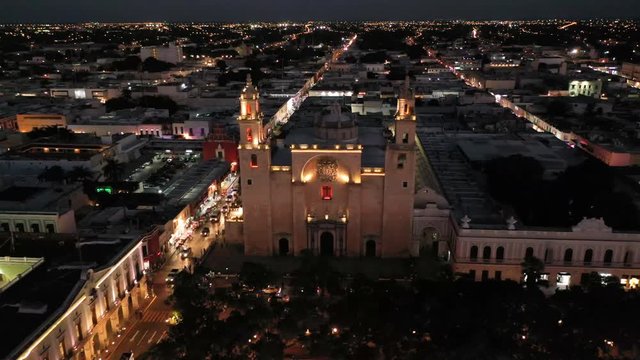 Aerial camera at night pulling back from the Cathedral of Merida, Yucatan, Mexico and revealing the twinkling lights of the city.