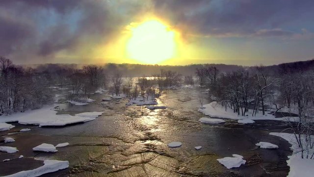 The motion of clouds, snow, water, and rising sun spin a mesmerizing dance of natural beauty, aerial view.