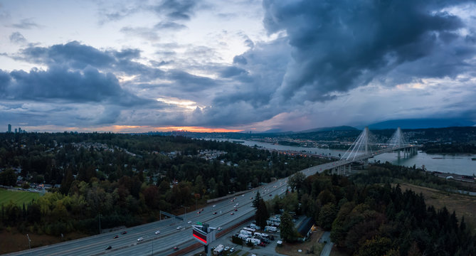 Aerial panoramic view of Trans Canada Highway near the Port Mann Bridge during a dramatic cloudy sunset. Taken in Surrey, Vancouver, BC, Canada.