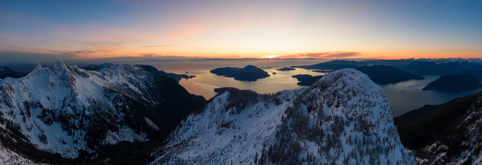 Aerial panoramic view of Howe Sound Mountains during a vibrant winter sunset. Taken near Lions Bay, North of Vancouver, BC, Canada.