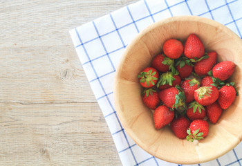 Strawberry in bowl on wood table background.