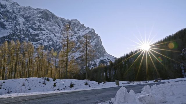 Beautiful winter landscape with a car passing by the road during the sunset. Triglav National Park. Slovenia. Flat plane