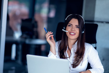 Portrait of happy smiling female customer support phone operator at workplace.