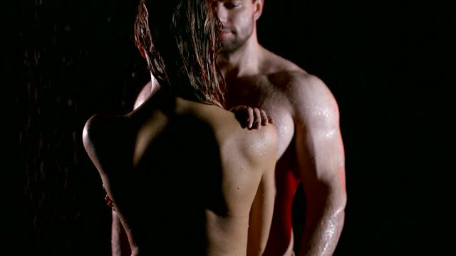 excited strong man is touching naked body of young fragile woman standing back, both are wet