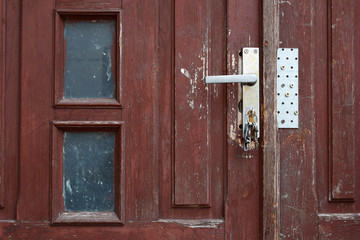 Old dirty brown wooden outer door with keys in keyhole.