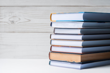 A stack of books lying on the table on a light wooden background. Back to school. Education background.