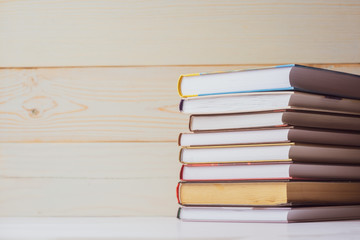 A stack of books lying on the table on a light wooden background. Back to school. Education...
