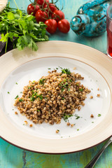 cooked buckwheat on white plate with berry juice on blue wooden table