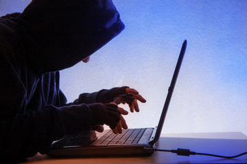 a hooded person sits in front of a computer