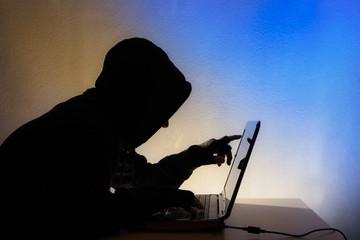 a hooded person sits in front of a computer