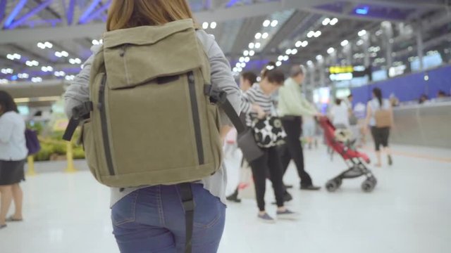 Slow motion - Young Asian backpacker woman walking in terminal hall while going to boarding flight at the departure gate in international airport. Lifestyle backpack tourist travel holiday concept.