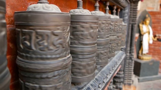 Row of aged religious prayer wheels or drums with mantra Om Mani Padme Hum in yard of temple, Durbar Square, Nepal, Kathmandu. Tibetian buddhism