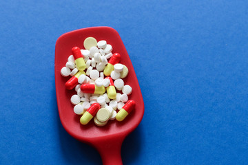 Medicine expenses. Various medicines and pills on red spoon with copy space