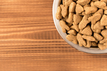Bowl with dog food on a wooden table. Close up.