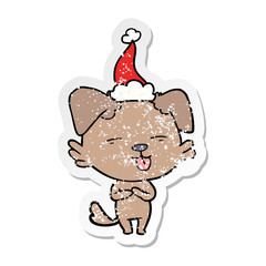 distressed sticker cartoon of a dog sticking out tongue wearing santa hat