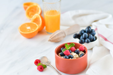 oatmeal with organic blueberries and raspberries, fresh orange juice and grapes. light background, selective focus and copy space, Breakfast concept. diet, healthy food