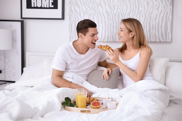 Obraz na płótnie Canvas Happy couple having breakfast together in bed