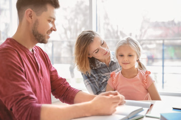 Little girl with parents doing homework at home