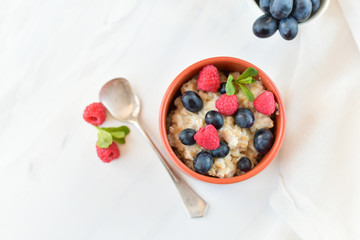 oatmeal with organic blueberries and raspberries, fresh orange juice and grapes. light background, selective focus and copy space, Breakfast concept. diet, healthy food