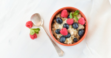 oatmeal with organic blueberries and raspberries, fresh orange juice and grapes. light background, selective focus and copy space, Breakfast concept. diet, healthy food